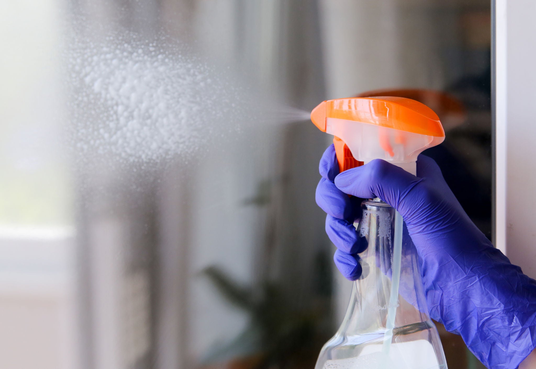 Woman cleaning a window with cleaning sprayer.