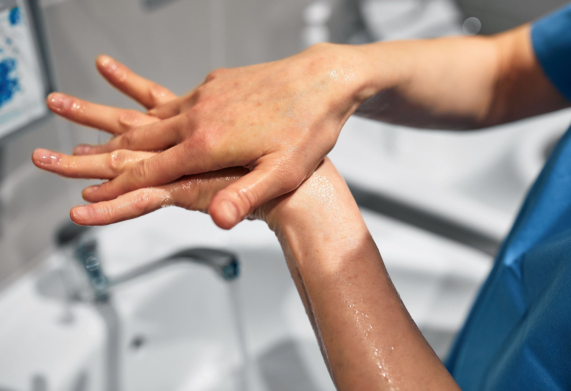 Close-up of a doctor washing his hands using a disinfectant dispenser..