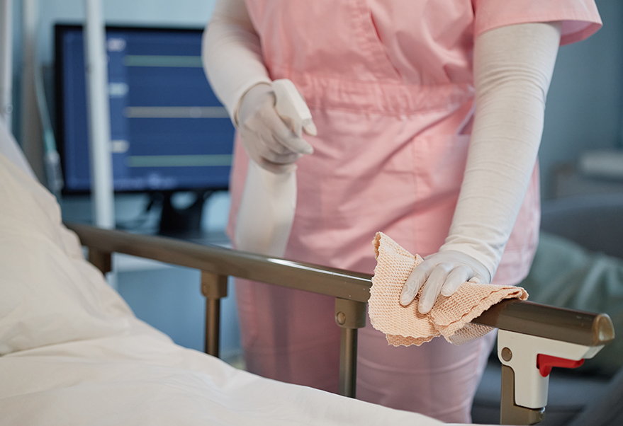 Cleaning hospital bed with sanitizing product in healthcare facility