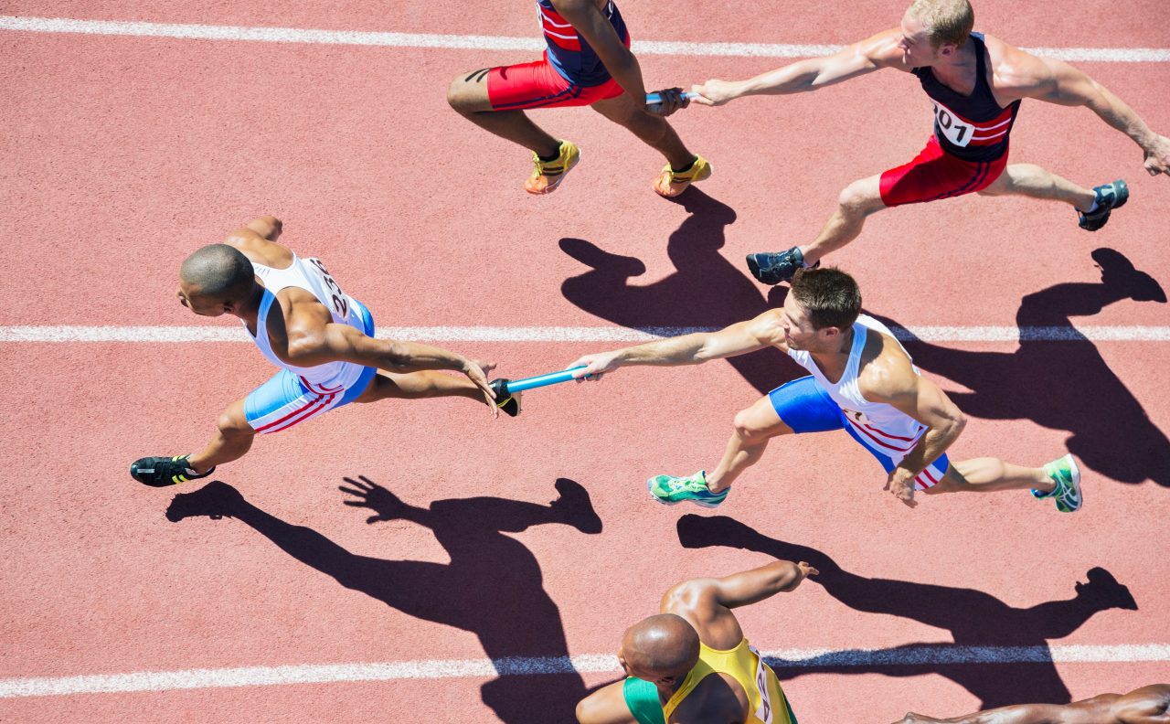 Relay runners passing batons on track