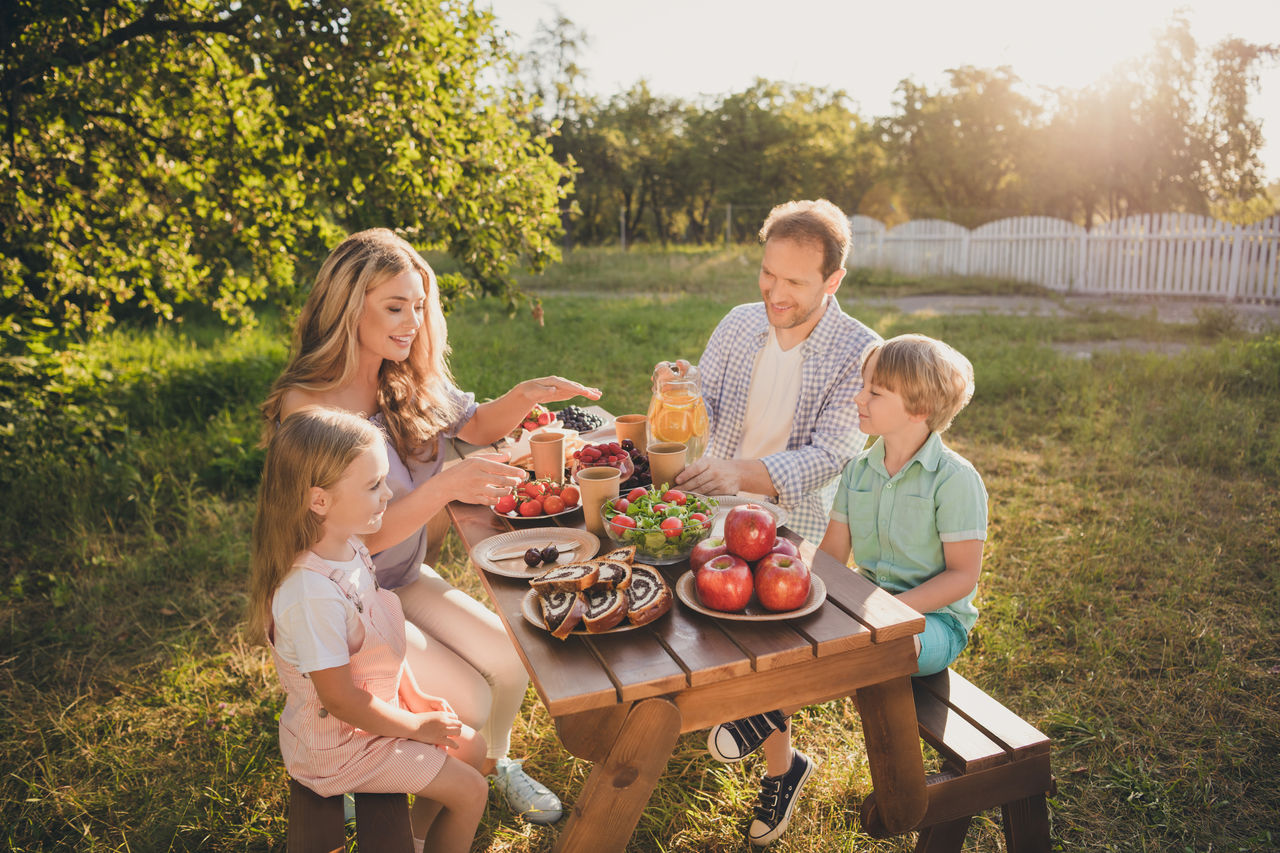 Photo of full big family four people gathering sit bench relax breakfast table drink citrus juice eat fruits vegetables salad generation warm weather comfort home park backyard outdoors